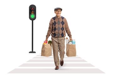 Wall Mural - Elderly man with grocery bags crossing street at traffic lights