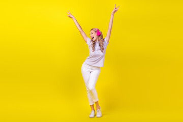 Poster - Full size photo of funky girl wear violet polo white trousers in headphones showing v-sign sing song isolated on yellow color background