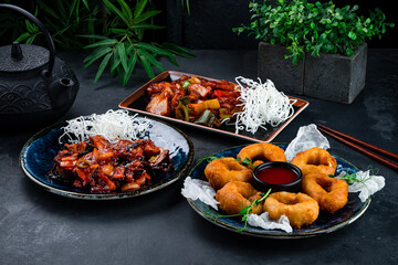 Wall Mural - Asian food chicken fillet with shiitake mushrooms, onion, celery, sweet pepper and crispy squid rings in dough with sauce and microgreens.