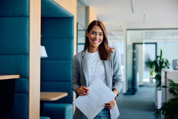 Wall Mural - Young happy businesswoman in office looking at camera.