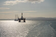 Oil Platform and offshore wind turbine installation ship in the bay of Invergordon during sunset, view from the distance, Scotland