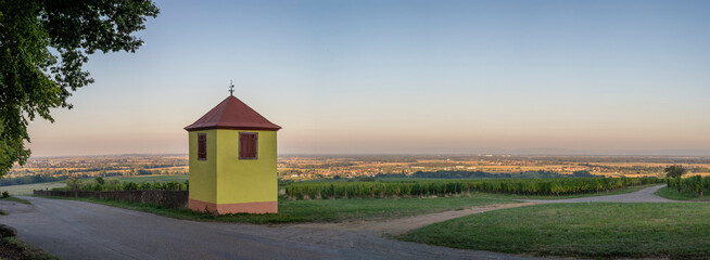 Wall Mural - Heiligenstein, France - 09 07 2022: The yellow tiny building and the vineyard at sunset.