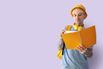 Wall Mural - Tattooed male student with notebook on lilac background