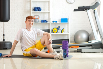 Poster - Sporty redhead man with earphones and mobile phone listening to music in gym