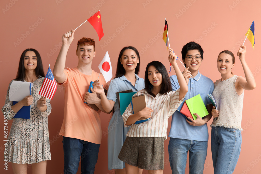 Young students of language school with flags on pink background