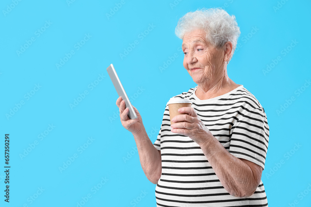 Senior woman with tablet computer and cup of coffee on blue background