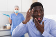 Portrait of unhappy worried afro american man after cosmetic procedure at clinic of esthetic medicine