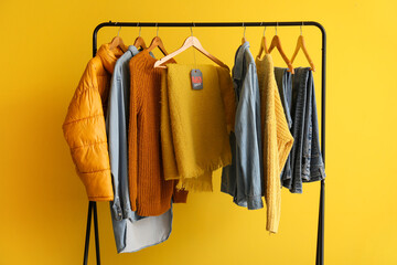 Poster - Rack with different clothes against yellow background. Black Friday sale