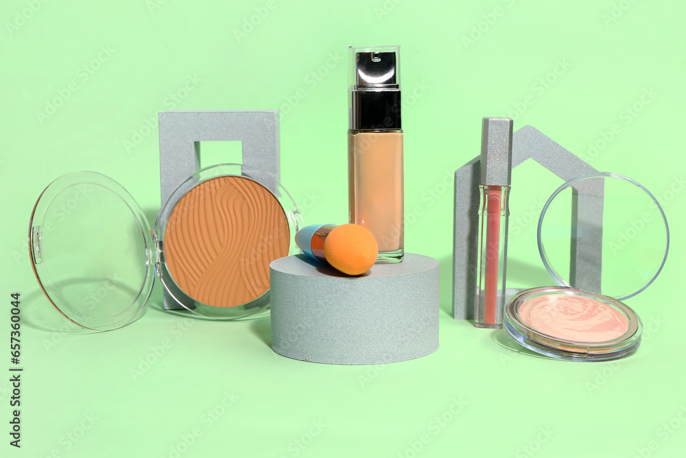 Different makeup cosmetics on green background