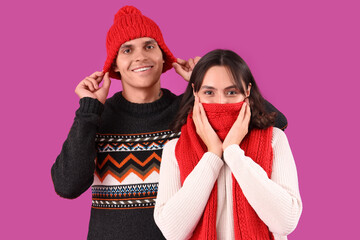 Wall Mural - Happy young couple in warm clothes on purple background