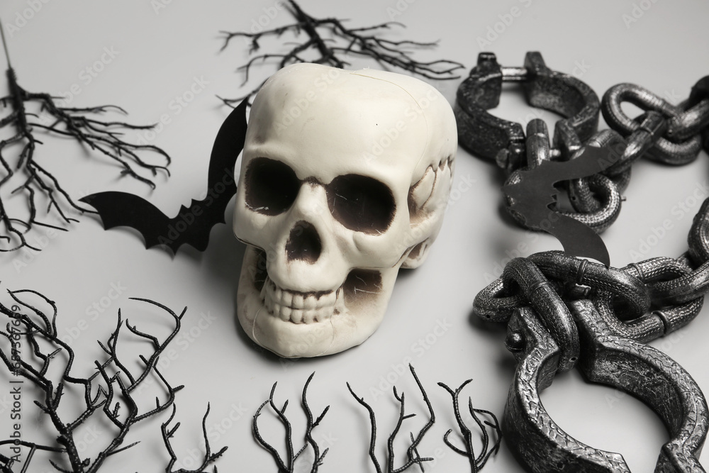 Halloween composition with skull, branches and shackles on grey background, closeup