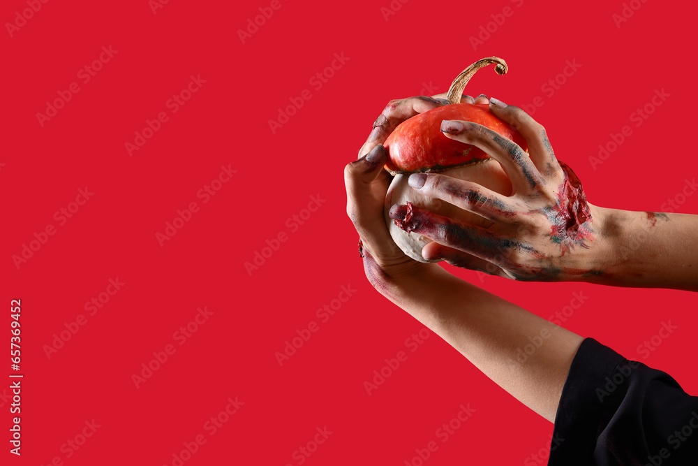Zombie hands with pumpkin on red background. Halloween celebration