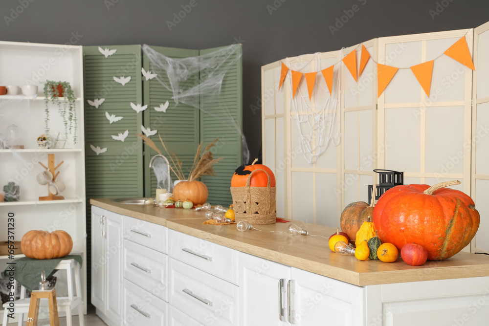 Interior of kitchen decorated for Halloween with white counters and pumpkins