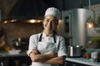 Portrait of beautiful female chef in uniform standing on modern kitchen restaurant, crossing arms and looking at camera