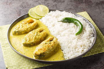 Wall Mural - Hilsa fish in Mustard Sauce or shorshe Ilish served with white rice closeup on the plate on the table. Horizontal