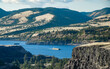A barge filled with wheat for animal feed being pushed by a tugboat upstream in the Columbia River Gorge. Seen from Tom McCall Preserve in Mosier, Oregon