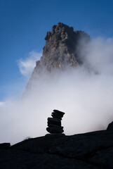 Fototapete - A cairn and clouds in the mountains.