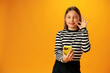 © fotofabrika - Stylish teen girl using smartphone over yellow background in studio
