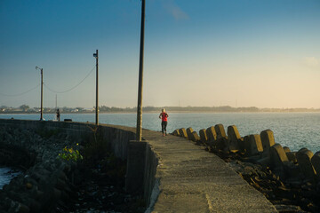 Wall Mural - A woman running in the morning around the beach.