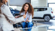 © Dragana Gordic - Happy woman buying a car and closing the deal with a handshake with the saleswoman at the dealership. Smiling car saleswoman discussing a contract with a female customer.