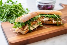 sandwich with microgreens, chicken, and mayo on a fresh baguette