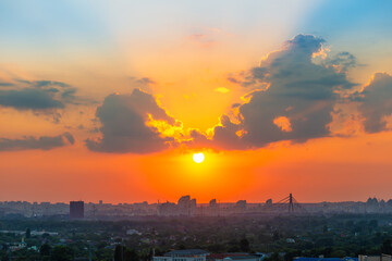 Wall Mural - Sunset in city with buildings, sun and sunset clouds. Kyiv, Ukraine