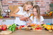 Two little girls in the kitchen with fresh vegetables. Healthy food concept. Happy sisters.