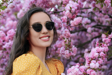 Canvas Print - Stylish woman in sunglasses near blossoming sakura tree on spring day