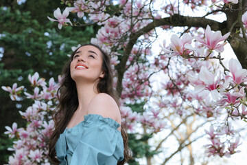 Wall Mural - Beautiful woman near blossoming magnolia tree on spring day