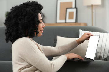 Poster - Happy young woman using laptop on sofa indoors