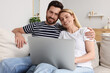 © New Africa - Happy couple with laptop on sofa at home