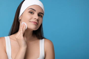 Poster - Young woman with cotton pad on light blue background. Space for text