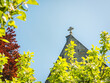 christian cross on top of the church seen through the trees on sunny blue sky day