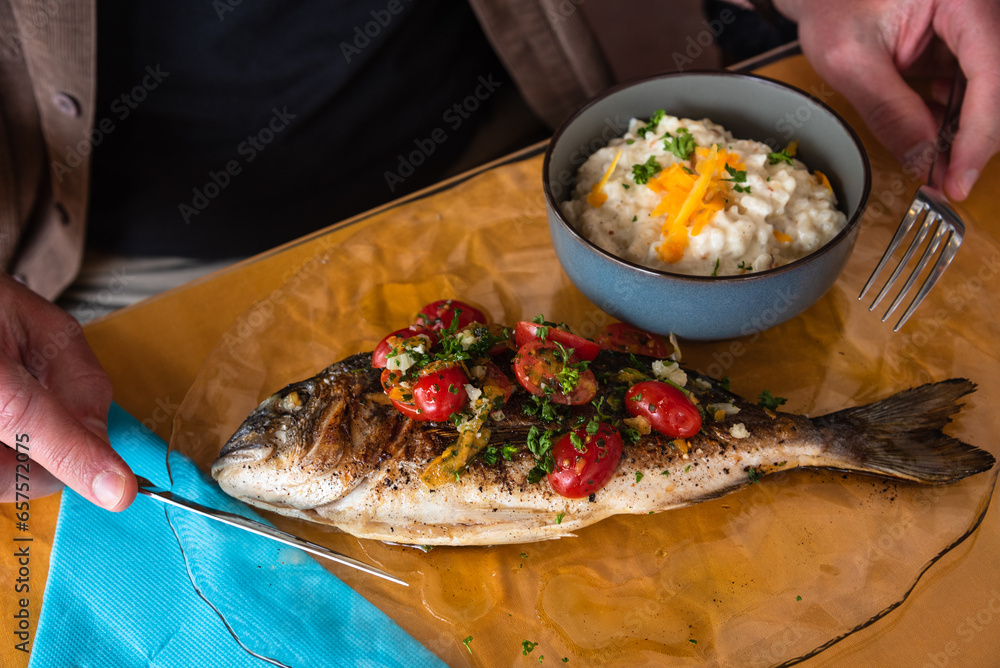 Man Eating Grilled Dorada Fish And Rice With Celery Root Puree In A man-eating-grilled-dorada-fish-and-rice-with-celery-root-puree-in-a