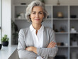 © Islam - Smiling confident stylish mature middle aged woman standing at home office. Mature businesswoman, gray-haired lady executive business leader manager looking at camera arms crossed