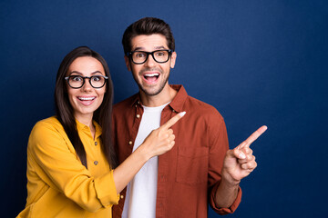 Sticker - Photo of two impressed cheerful corporate colleagues indicate finger empty space proposition isolated on blue color background