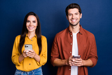 Poster - Photo of two positive nice young people toothy smile hold use smart phone texting isolated on blue color background