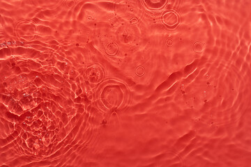 Wall Mural - Water red surface abstract background. Waves and ripples texture of cosmetic aqua moisturizer with bubbles.