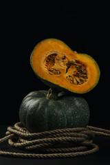 Wall Mural - Green pumpkin on a dark background. Half a pumpkin next to a whole pumpkin