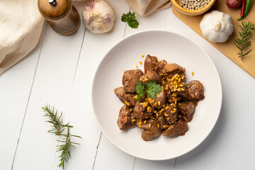 Wall Mural - Fried chicken Liver with Garlic,Stir fry sliced liver with peppercorn and garlic in white plate.Top view