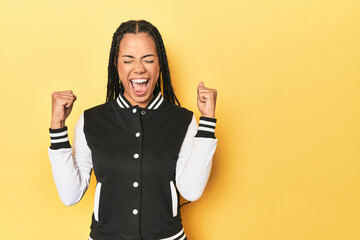 Wall Mural - Indonesian woman in classic black baseball jacket raising fist after a victory, winner concept.