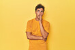 © Asier - Young Latino man posing on yellow background is saying a secret hot braking news and looking aside