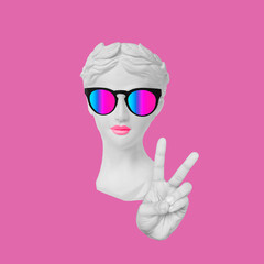 Wall Mural - Antique female statue's head in bright sunglasses showing a peace gesture with hand isolated on pop pink color background. Trendy collage in magazine surreal style. Contemporary art. Modern design
