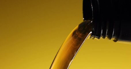 Wall Mural - closeup of pouring fresh new car motor oil from bottle on yellow background. engine maintenance