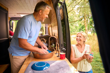 Wall Mural - Senior Couple Enjoying Camping In Countryside Relaxing Inside RV And Doing Chores Together