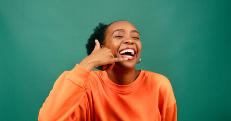 Wall Mural - Cute young woman makes Call Me symbol with hand, flirting, green studio