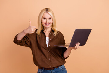 Sticker - Photo of friendly young positive woman thumb up like good efficiency laptop good capacity accumulator isolated on beige color background