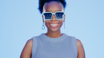 Portrait, sunglasses and smile, black woman in studio with cool, trendy summer fashion and creative mockup. Happiness, luxury eyewear and excited, fun model with designer frame on blue background.