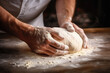 © pilipphoto - Male hands kneading dough on the wooden table, close-up