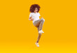© Studio Romantic - Cheerful boy is having fun and fooling around, dancing on yellow-orange background in the studio. Funny boy in curly wig with bent arms shows movement YES. Beside myself with joy and happiness.